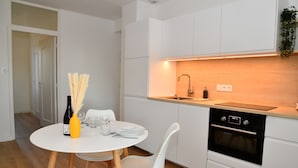 Een moderne keuken met witte kastjes, een houten aanrechtblad en een ingebouwde oven.