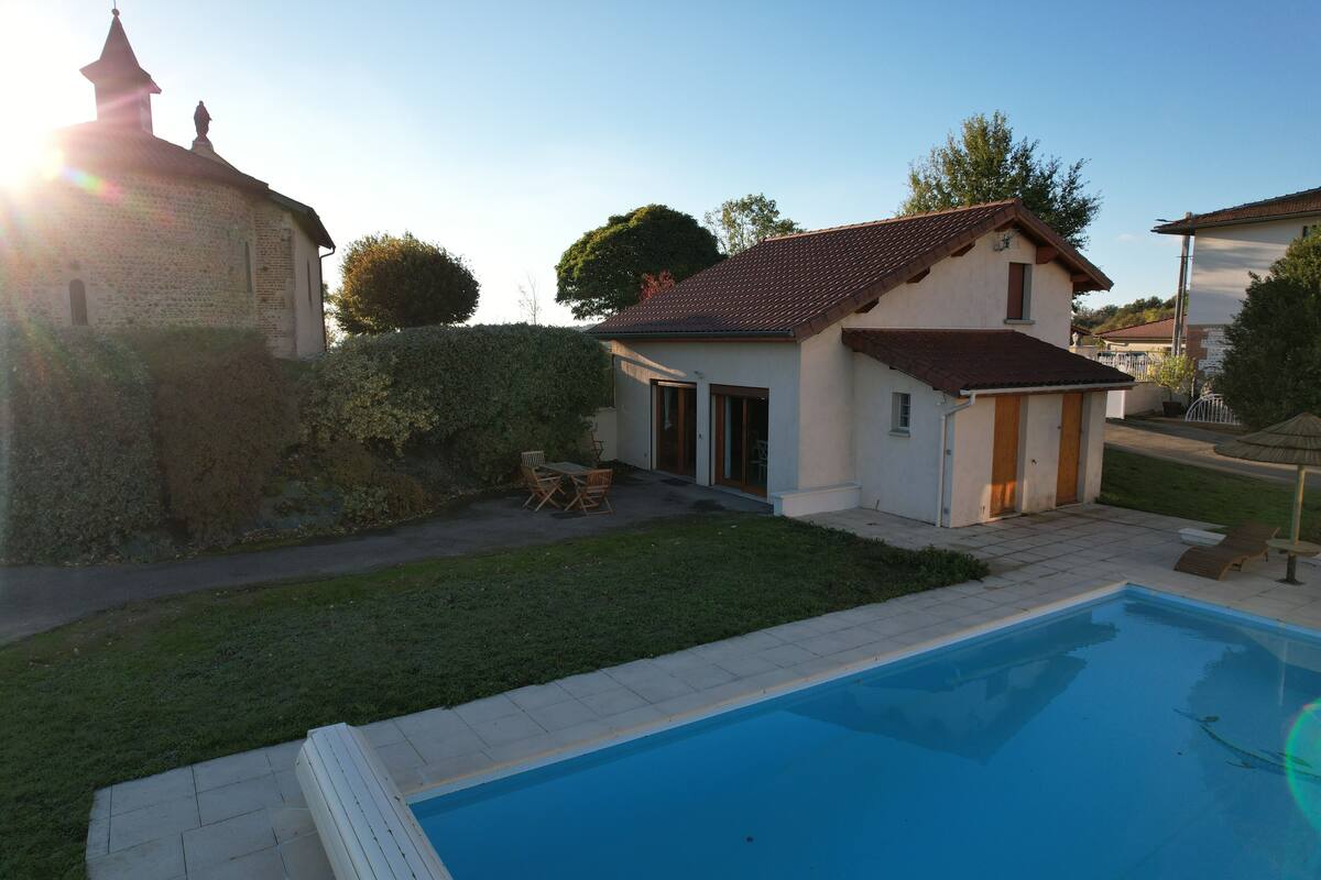 Il s’agit d’une propriété résidentielle dotée d’une piscine, d’un petit patio avec mobilier d’extérieur et d’un grand arbre en arrière-plan.