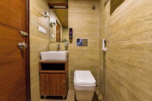 A compact bathroom with a wooden vanity, a white sink, and a toilet. - Naivara Boutique Hotel (Udaipur)
