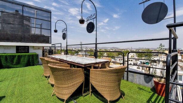 Un área de estar al aire libre con mobiliario de mimbre, una mesa y lámparas colgantes.