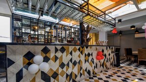 Una zona de bar con piso a cuadros, una barra con cristalería y una pared decorativa.