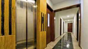 Un pasillo con ascensor, puerta de madera y suelo de mármol.