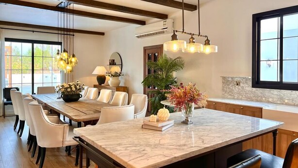 Un comedor amplio con una isla de mármol, sillas de madera y una lámpara colgante.