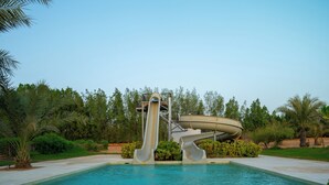 Una piscina con tobogán y escalera de caracol.