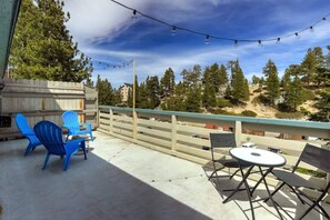 An outdoor patio with blue chairs, a table, and string lights.