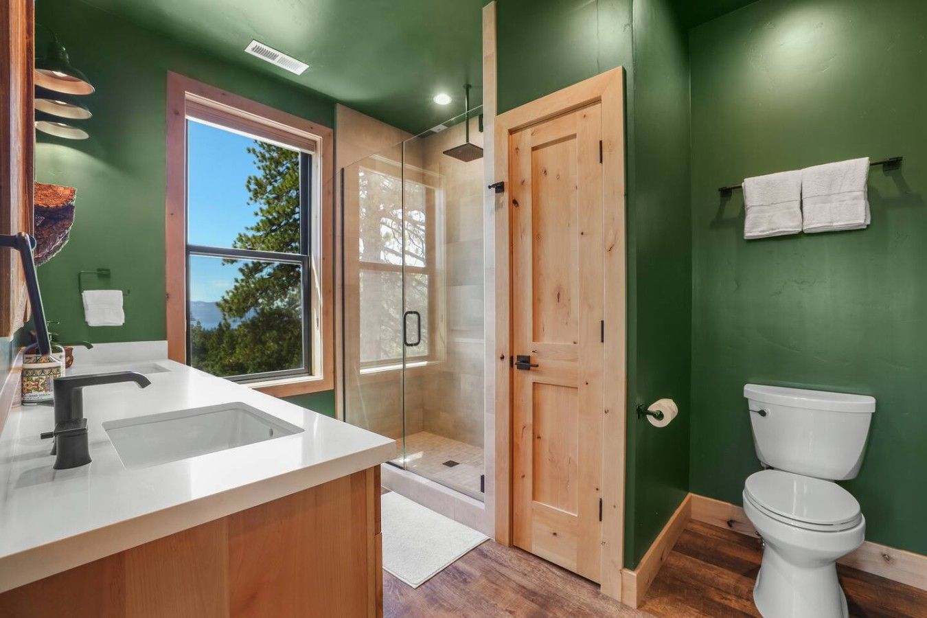A modern bathroom with a large window, a shower, and a toilet.