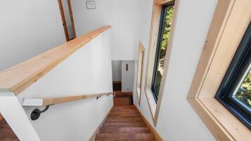 A narrow staircase with wooden handrails and a skylight on the right.