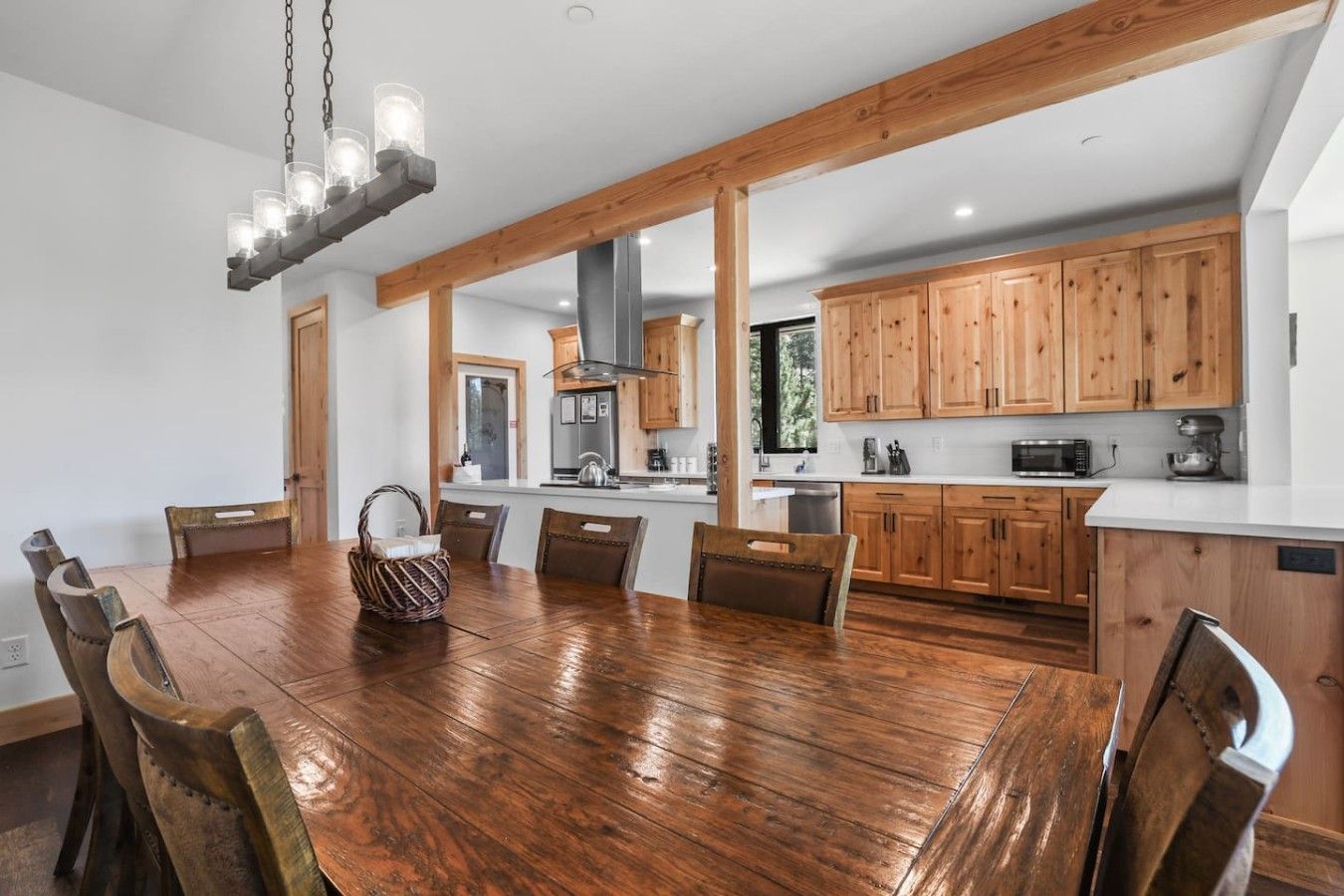 Una cocina amplia con armarios de madera, una mesa de comedor con sillas y una lámpara colgante.