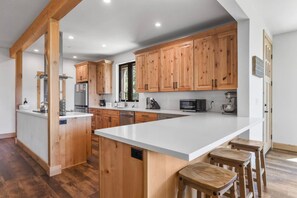 A modern kitchen with wooden cabinets, a large island, and bar stools.