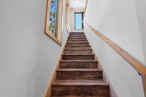A wooden staircase with a handrail, leading to a room with a window.