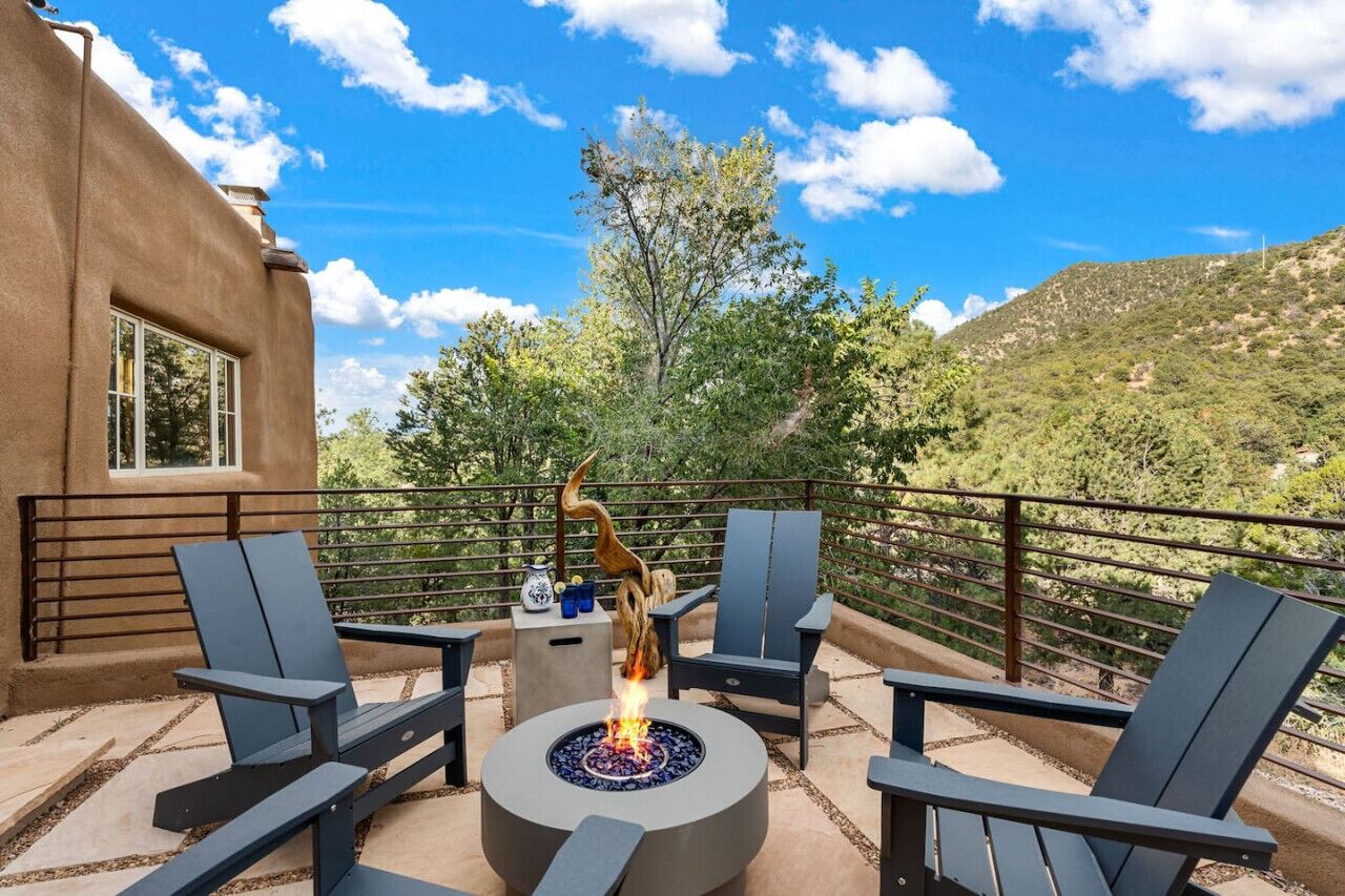 An outdoor patio with a fire pit, seating, and a view of a mountainous landscape.