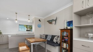 Una cocina moderna con una mesa y banco de madera, una estantería empotrada y un comedor con ventana.