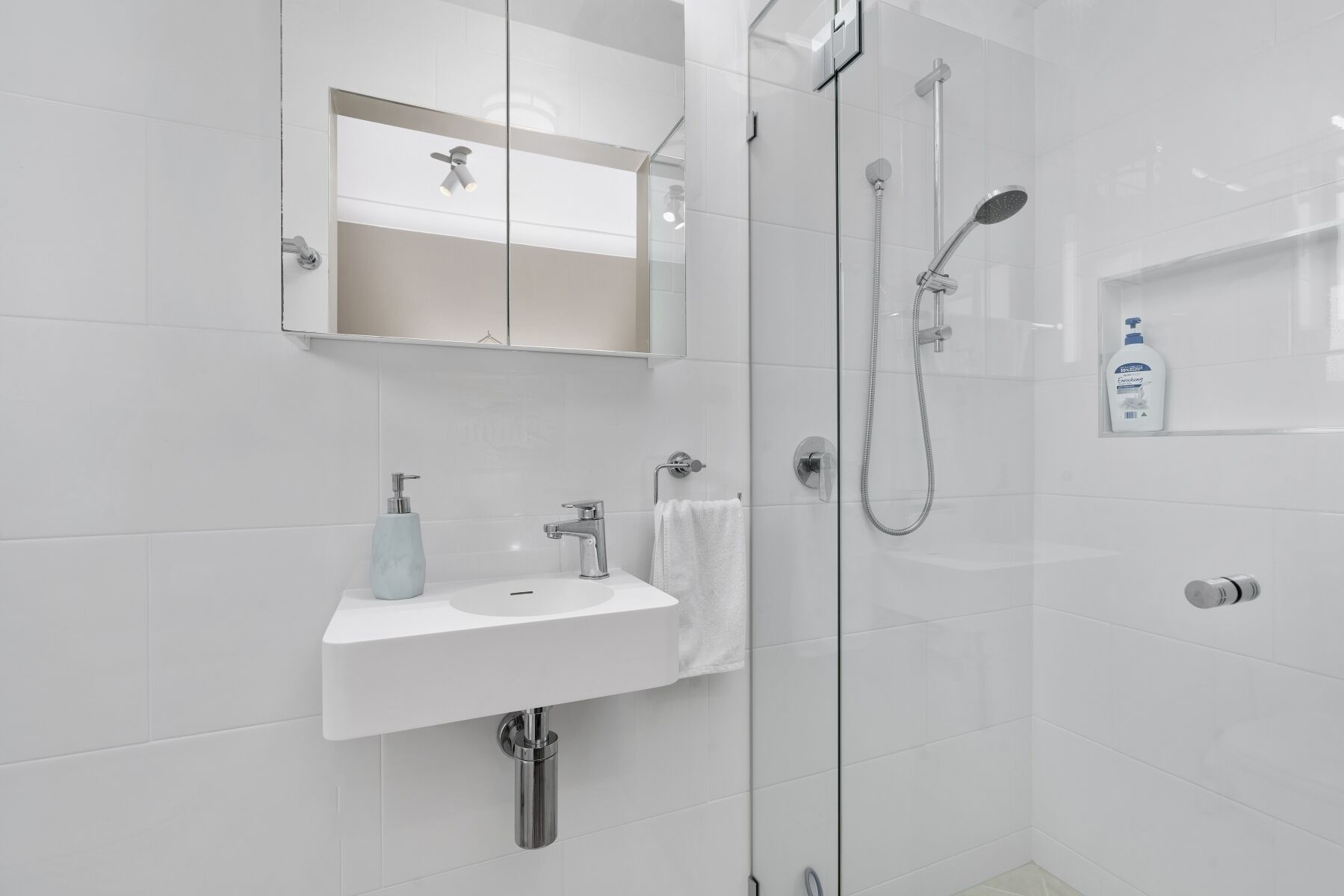 Ein modernes Badezimmer mit Waschbecken, Spiegel und Duschkabine aus Glas.