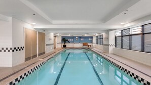 Una piscina con borde de mosaicos a cuadros, un mostrador de recepción y un reloj en la pared.