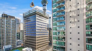 Un moderno edificio de gran altura con una cuadrícula de ventanas, rodeado de otros edificios altos.