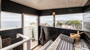 A balcony with a wooden ceiling, a view of the sea, a potted plant, a bench, and a wooden bucket. - Luxury townhouse with rooftop Sauna & Jacuzzi REF062 (Fuengirola)