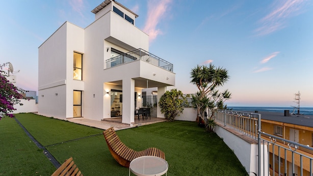 A modern two-story house with a balcony, a well-maintained lawn, and a view of the ocean. - Luxury townhouse with rooftop Sauna & Jacuzzi REF062 (Fuengirola)