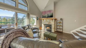 A spacious living room with a leather sofa, a fireplace, and a large window overlooking a balcony. - Benny's Place-Marble Canyon 404P1 (Area F (Columbia Lake/Windermere Lake))