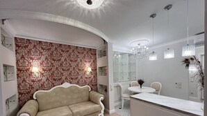 Un salon moderne avec un canapé beige, une table basse en verre et un lustre.