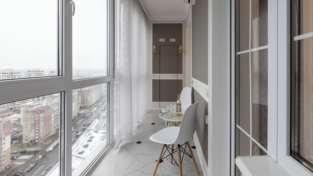 Un balcon donnant sur le paysage urbain, une petite table avec une chaise et une porte avec un interrupteur.