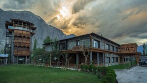 A large, multi-story building with a prominent tower and extensive outdoor seating area, set against a mountainous backdrop. - PC Legacy Skardu (Skardu)