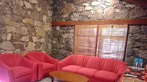 A room with a stone wall, a red sofa set, a wooden coffee table, and a patterned rug. - PC Legacy Skardu (Skardu)