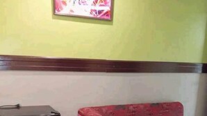 Ein Zimmer mit einem weißen Kühlschrank, einem rosa Sofa mit Kissen und einem gerahmten abstrakten Gemälde an der Wand.
