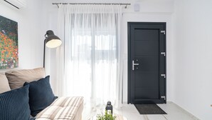 Una sala de estar moderna con un sofá, una lámpara, una puerta y un cuadro en la pared.