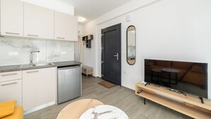 Eine moderne Küche mit eingebautem Geschirrspüler, einem Essbereich mit Sofa und Fernseher auf einem Holzboden.