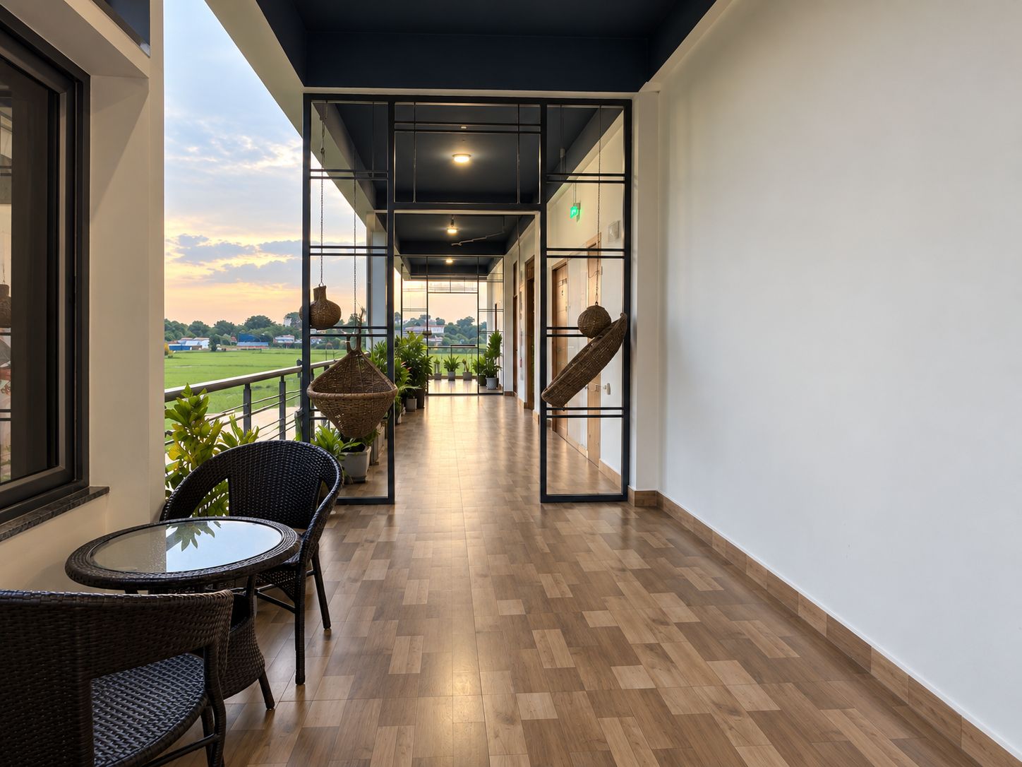 Un balcón con vistas a un campo verde, una cesta colgante y una mesa de mimbre con sillas.