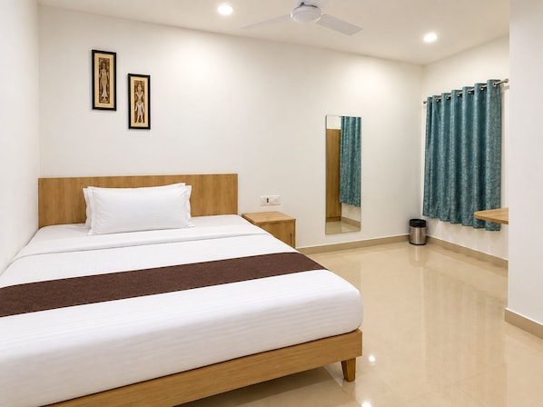 A hotel room with a bed, a nightstand, a mirror, a window with curtains, and a ceiling fan.