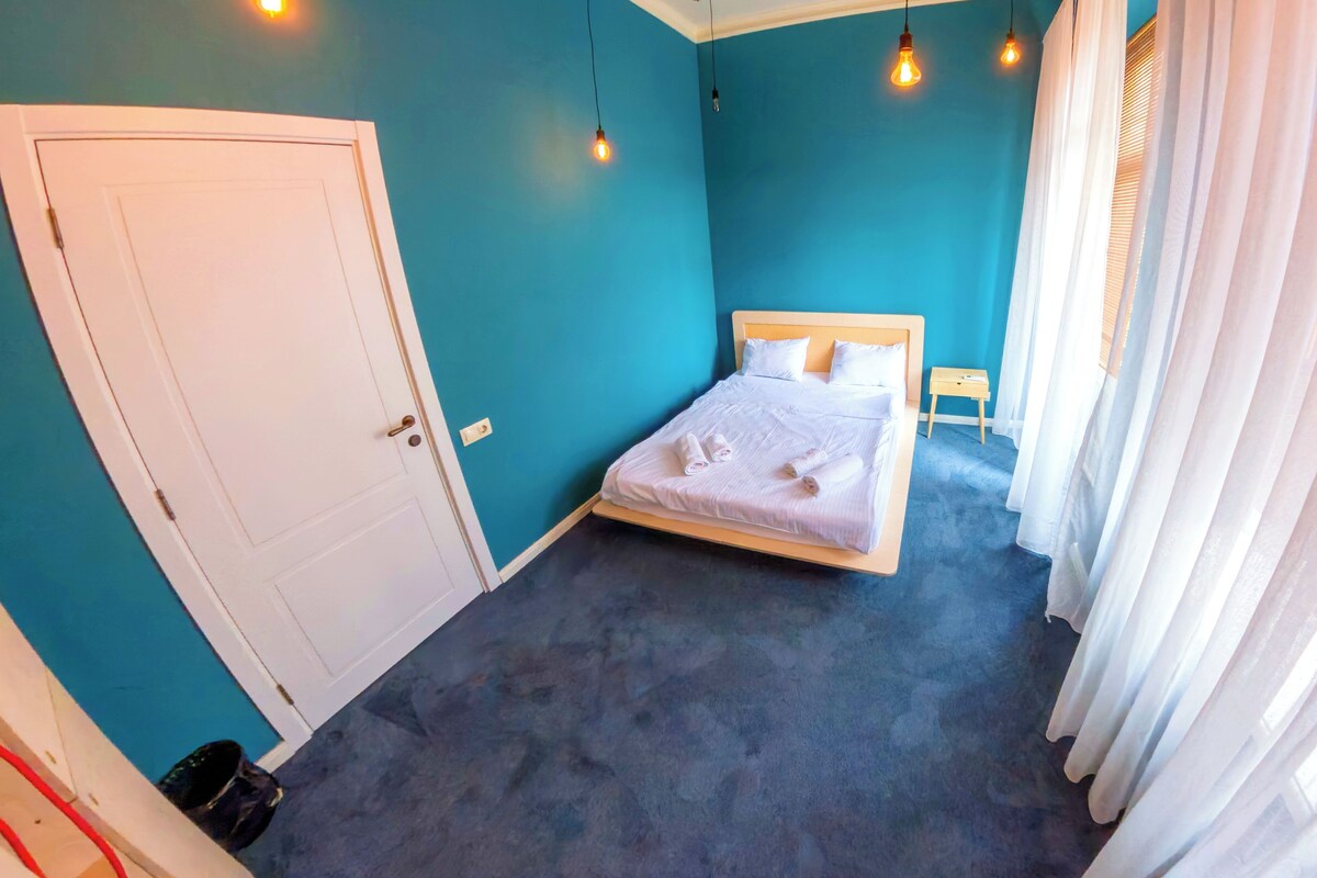 A bedroom with a bed, a door, and a small table.