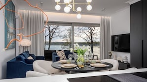Un salon moderne avec un coin repas, de grandes fenêtres donnant sur un lac et un mobilier contemporain.