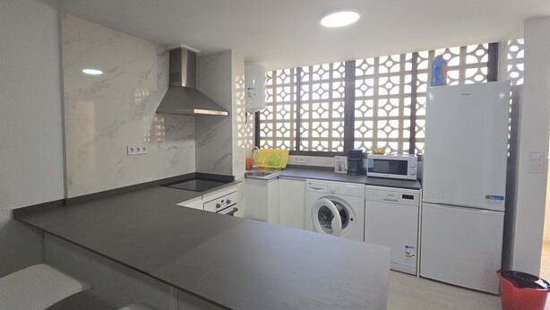 A compact kitchen with a washing machine, a microwave, and a refrigerator. - MARISCAL 3  2I (1  BEDROOM) (Benidorm)