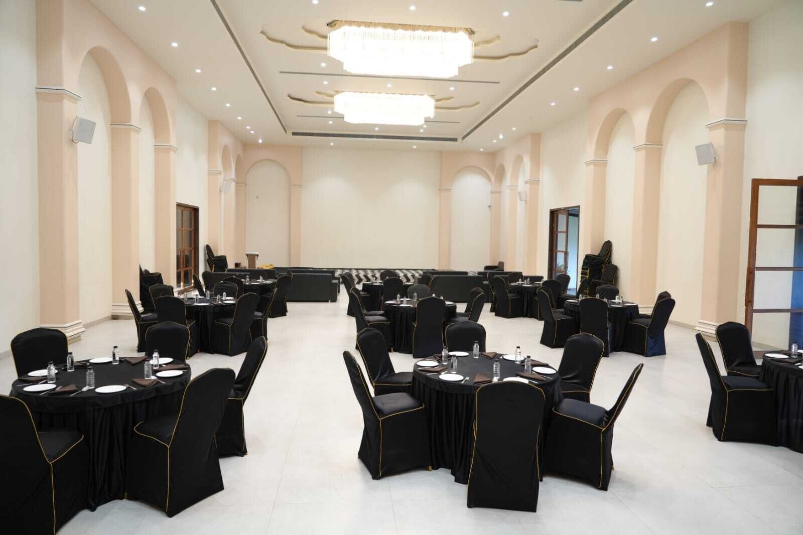 Un salón de conferencias con varias mesas y sillas, una araña y techos abovedados.