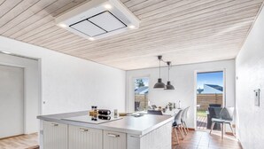 Une cuisine moderne dotée d’un îlot central, de meubles blancs et d’un luminaire au plafond.