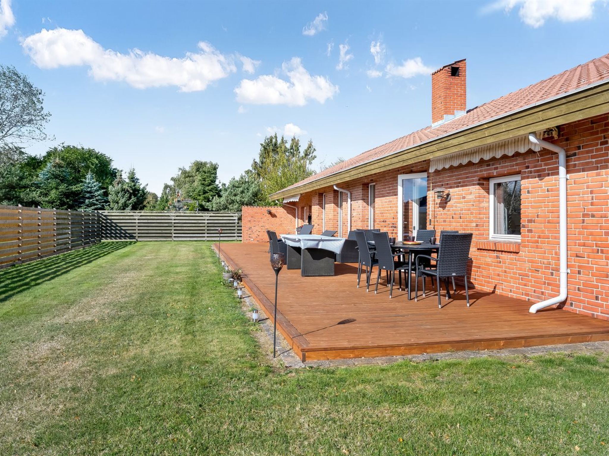 A brick house with a wooden deck and outdoor furniture.