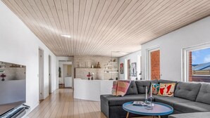 Un salon moderne avec un canapé gris, une table basse ronde et un plafond en bois.