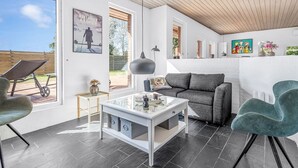 Un salon moderne avec un canapé blanc, un fauteuil vert et une table basse en verre.