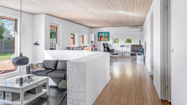 Un intérieur moderne avec un îlot central, un canapé, une table basse et un coin repas.