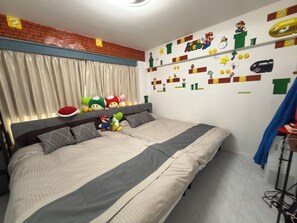 A bedroom with a bed, pillows, and a wall decorated with Super Mario characters.