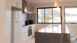 A modern kitchen with a large island, stainless steel appliances, and pendant lighting.