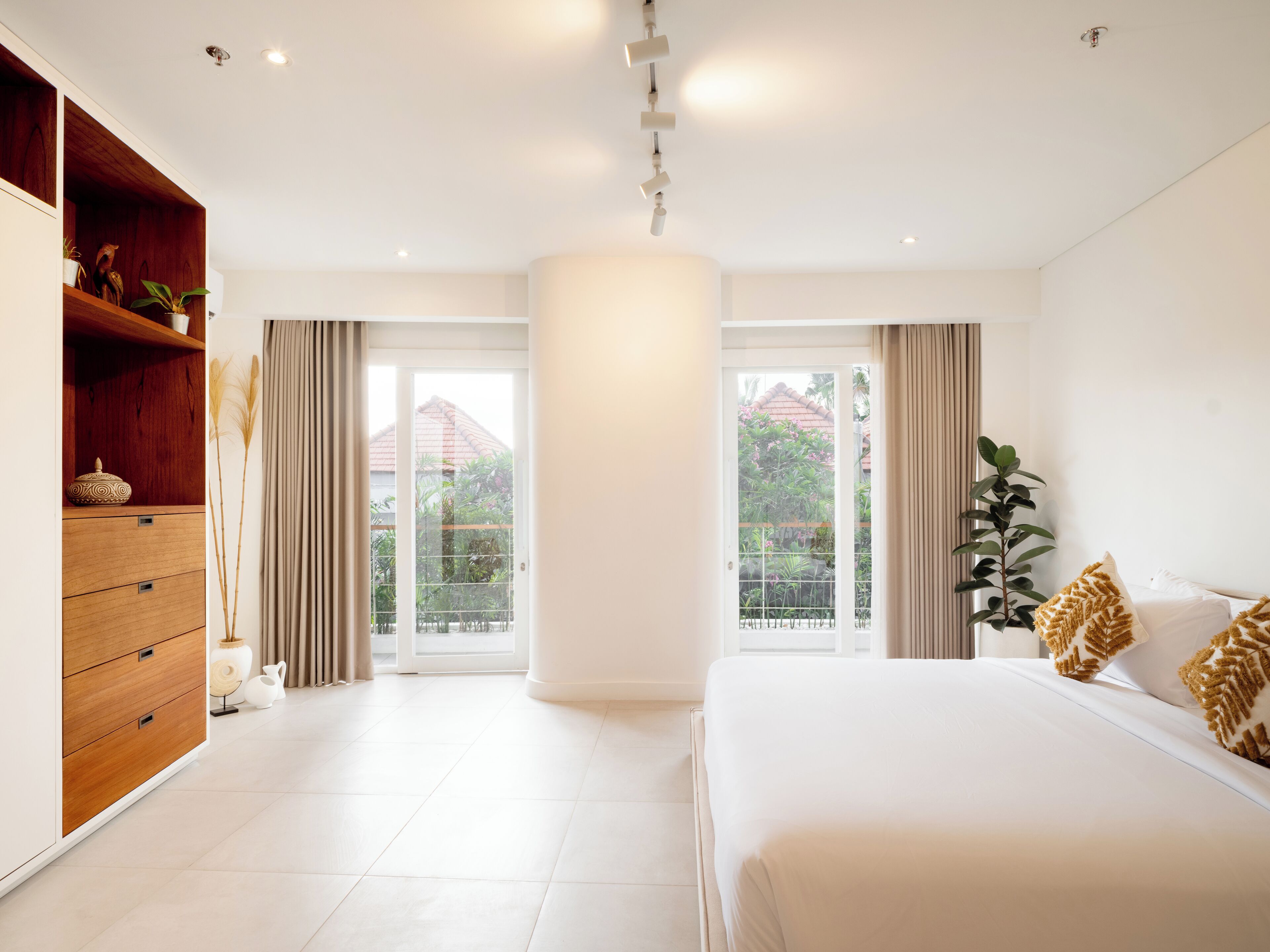 Une chambre moderne avec un grand lit, une armoire en bois et une vue sur un jardin, accessible par une porte coulissante.