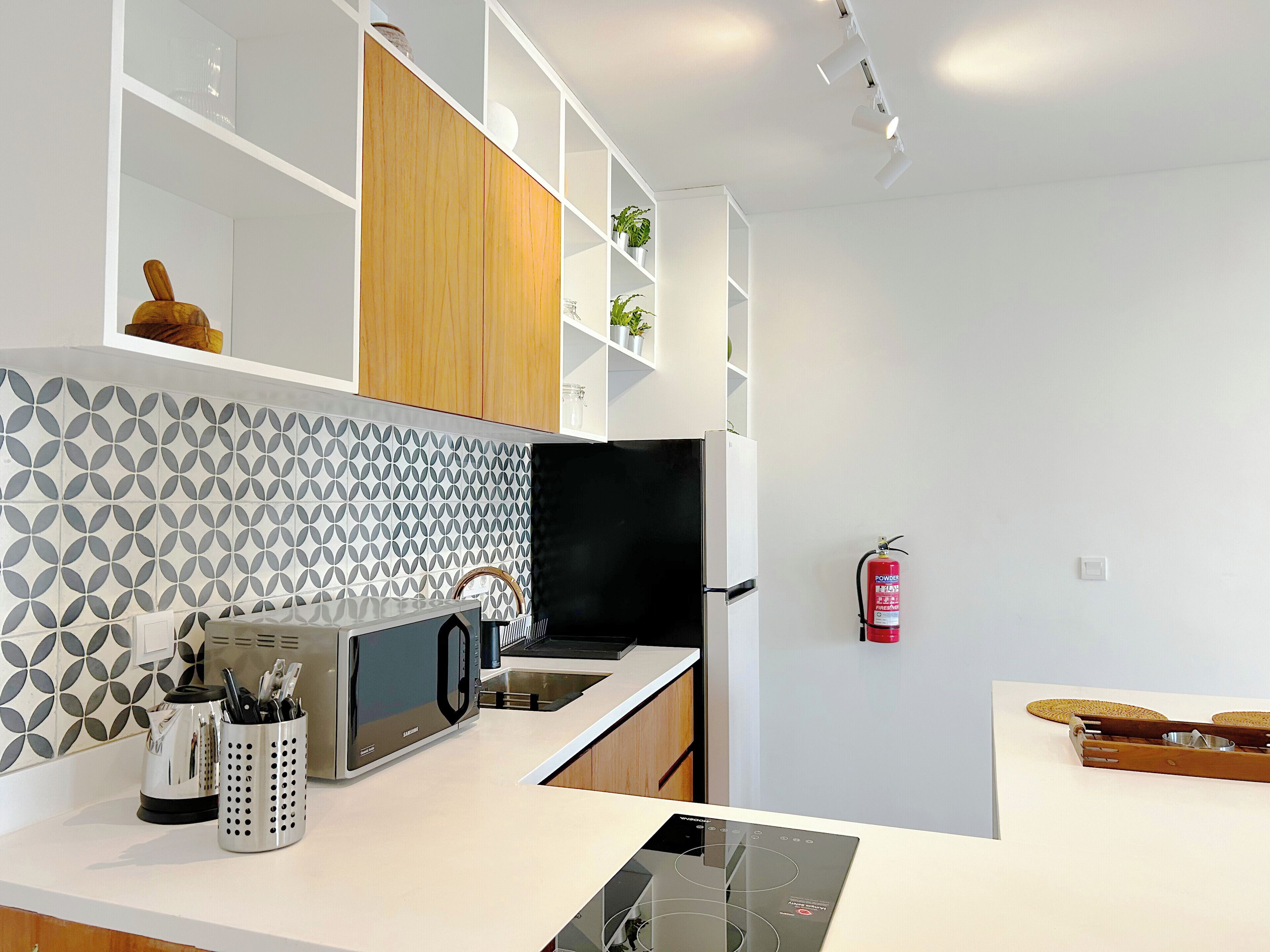 Cocina moderna con armarios blancos, salpicadero estampado y electrodomésticos de acero inoxidable.
