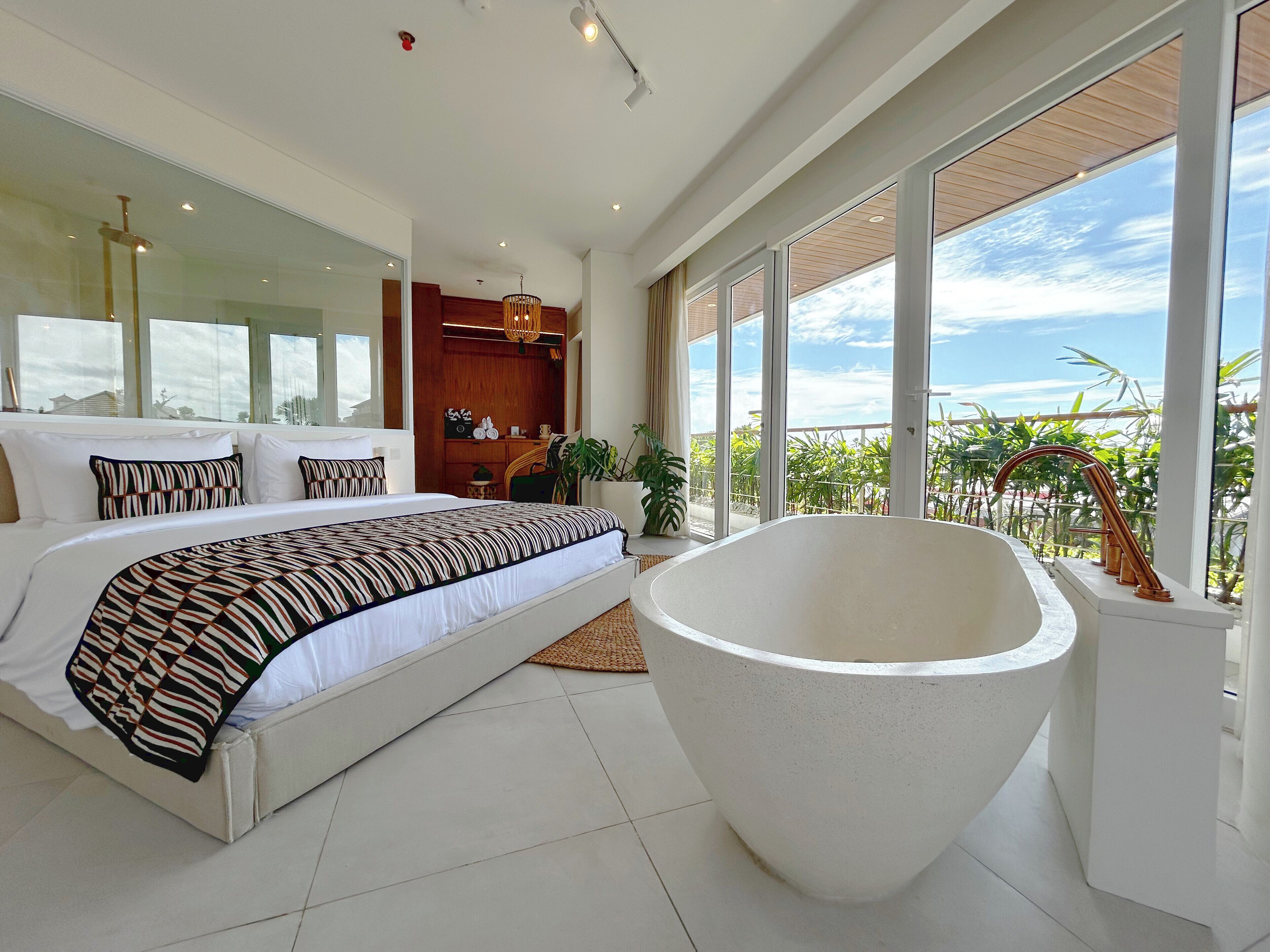 Una camera da letto moderna con un letto grande, una vasca da bagno e un balcone con vista.