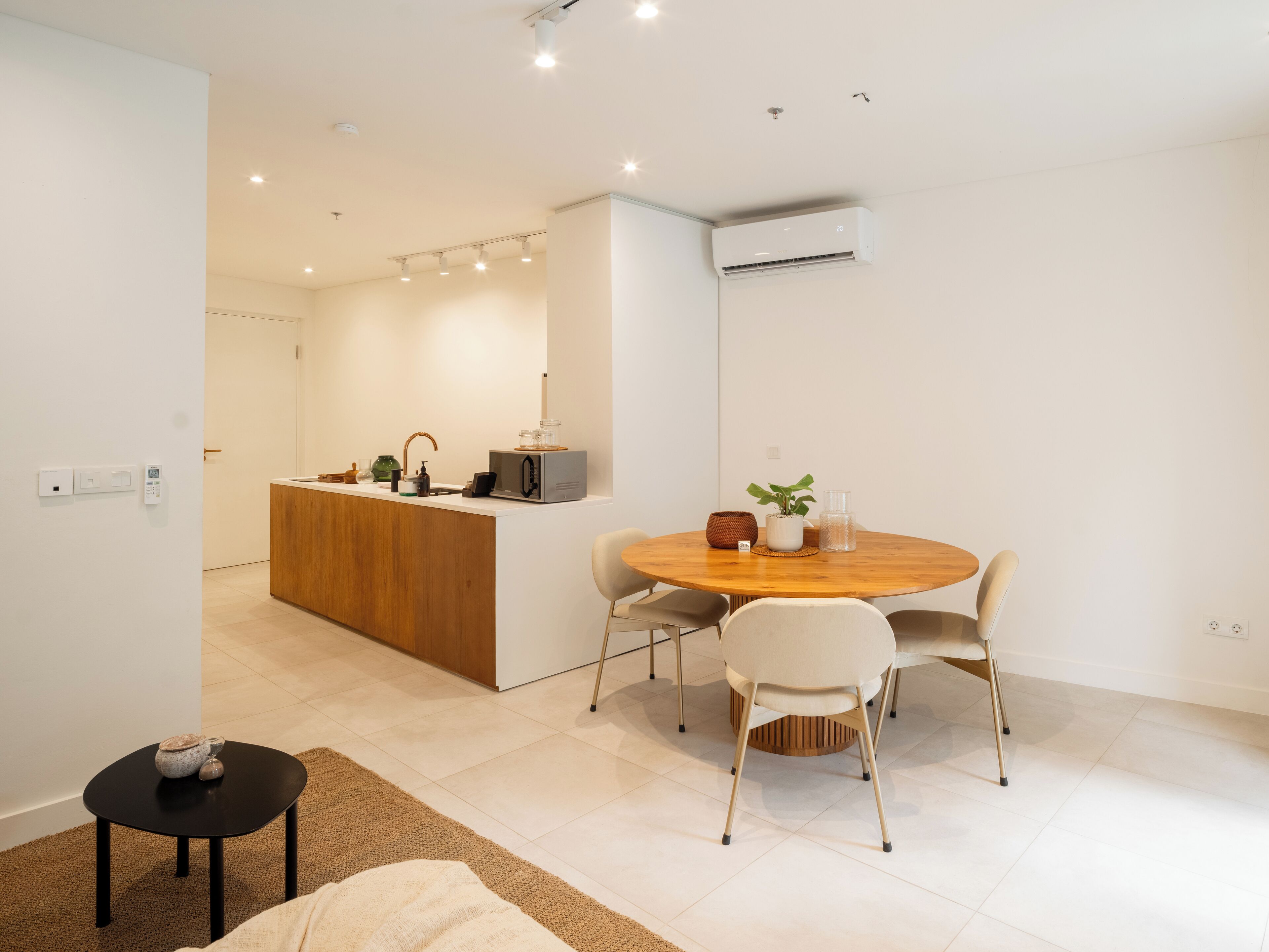 Een moderne keuken met een centraal eiland, een eethoek met een ronde tafel en stoelen, en een klein bijzettafeltje.