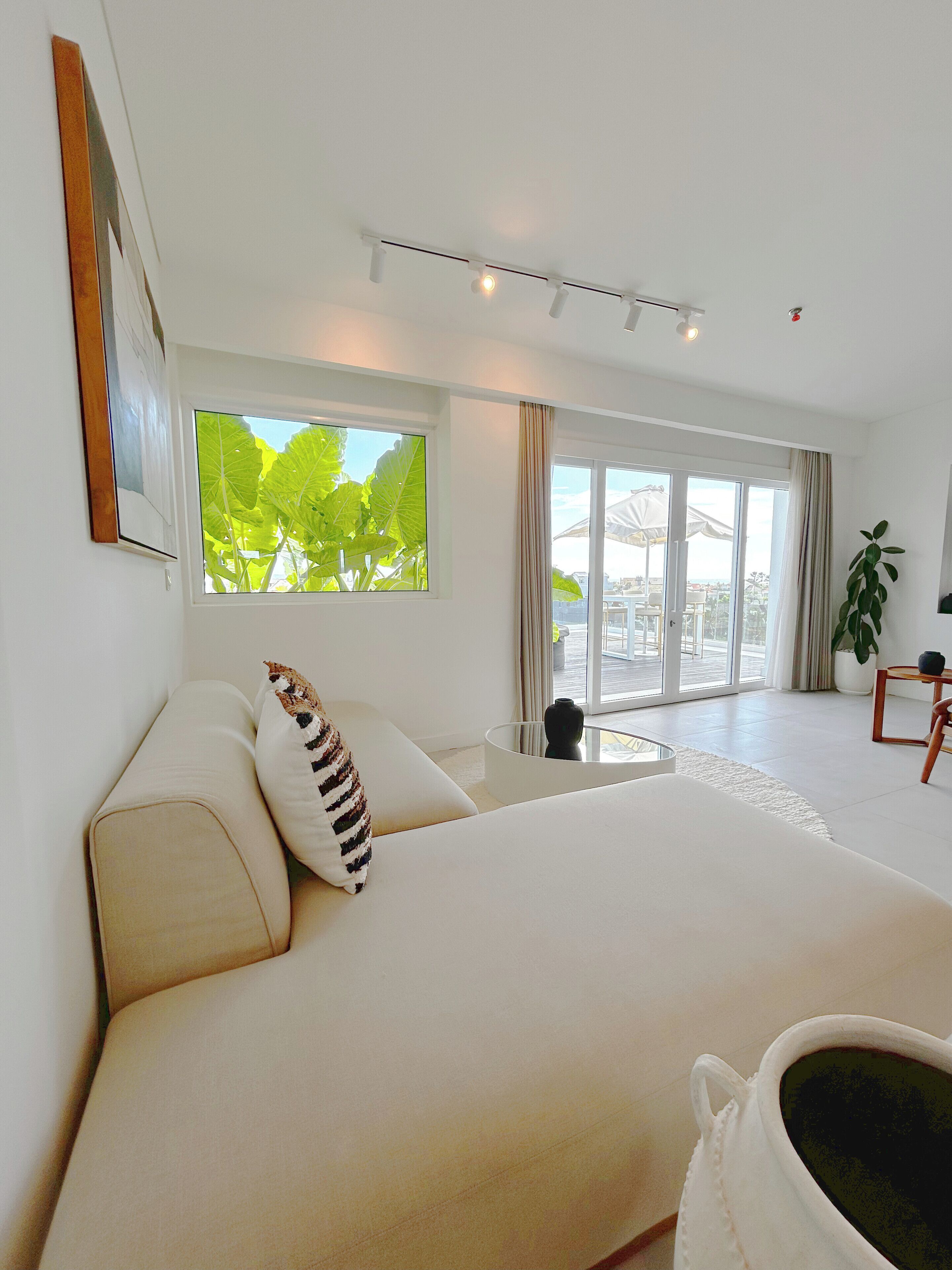A modern bedroom with a large bed, a window with a view, and a balcony.