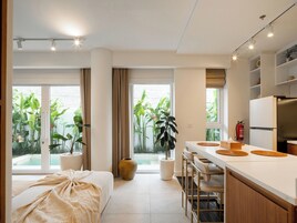 Una cucina moderna con un piano di lavoro bianco, sgabelli da bar e un'ampia finestra vista giardino.