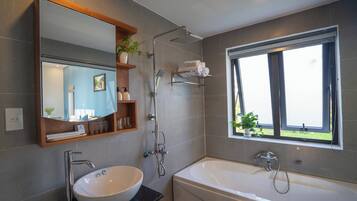 Een bad/douchecombinatie, een haardroger, pantoffels, handdoeken