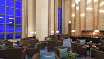 A hotel lobby with multiple seating areas, a fireplace, and large windows.